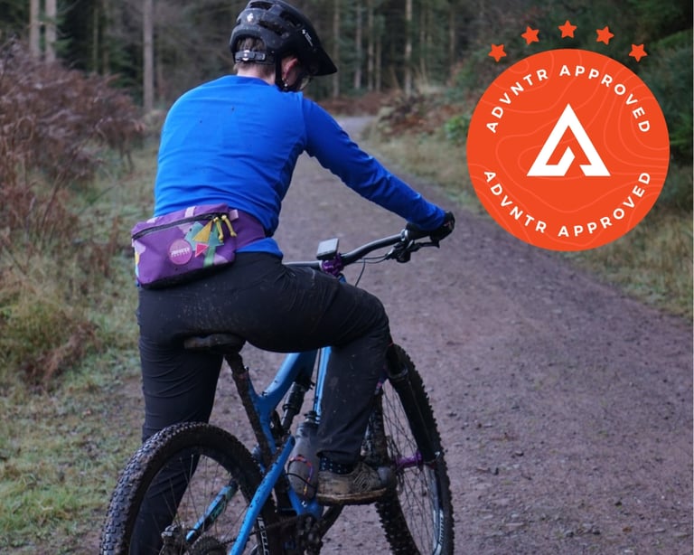Rider in Decathlon MH500 hiking trousers and a blue top on a mountain bike on a forest track, seen from behind.