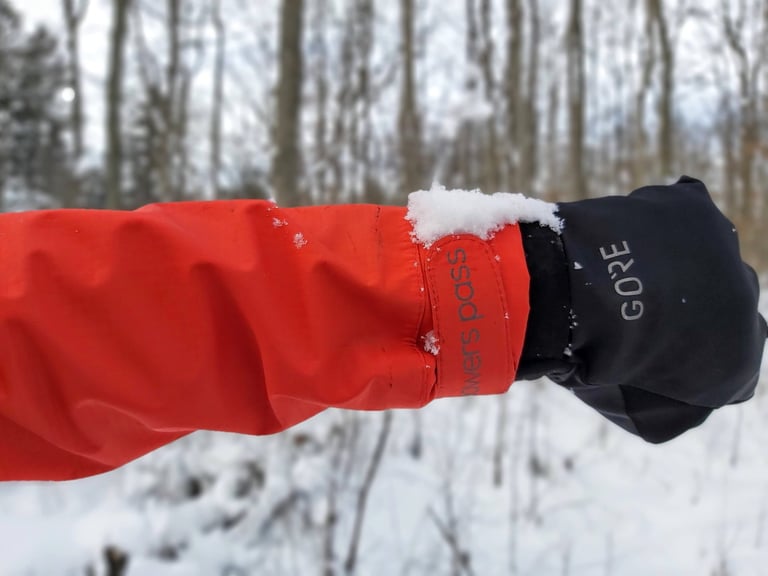 Velcro cuff strap on the red Showers Pass Refuge jacket sleeve, sitting over a Gore glove.