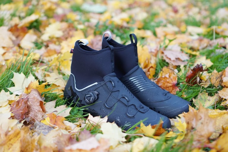Northwave Magma XC Core winter boots in black with neoprene cuffs and a BOA dial, standing in autumn leaves.