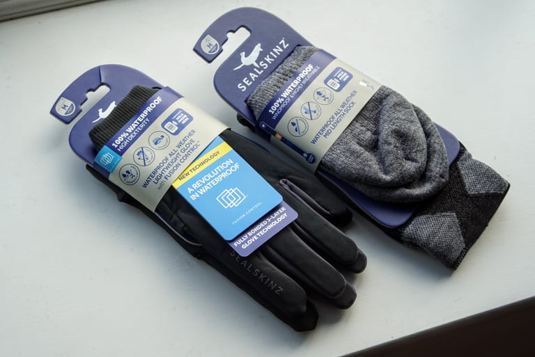 Sealskinz Fusion Control glove and sock packaging on a windowsill, labelled 100% waterproof.