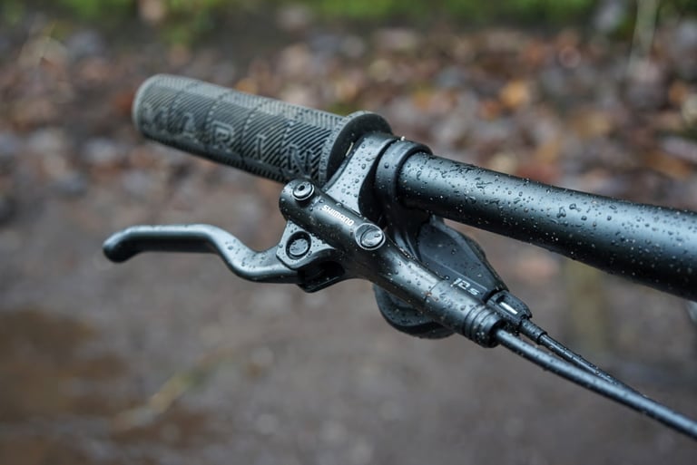 Shimano hydraulic brake lever and own-brand grip on the flat bar of the Marin DSX 2, beaded with rain.