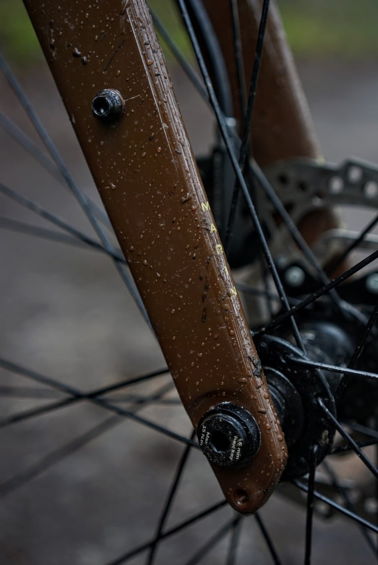 Marin DSX 2 fork leg with a mudguard and rack mount bolt above the thru-axle, wet with rain.