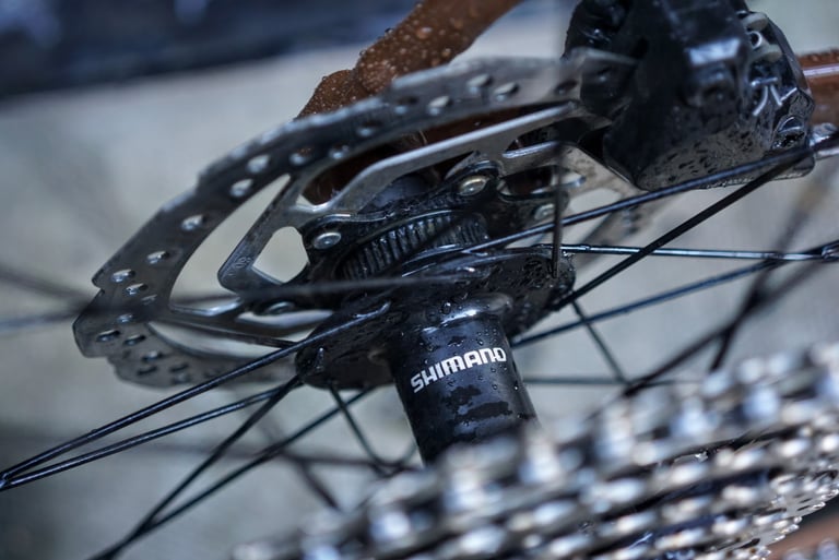 Shimano rear hub with a centrelock disc rotor and brake calliper on the Marin DSX 2, wet from rain.