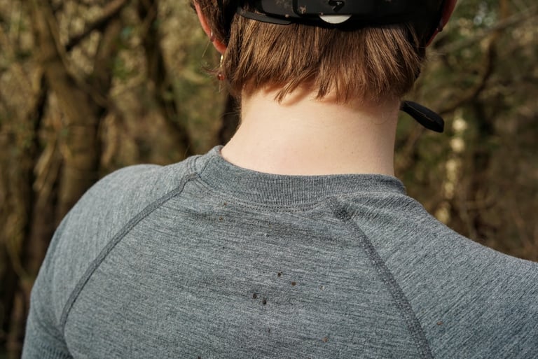 Close-up of the crew neck and flatlock sleeve seams on a grey Cascada merino baselayer, seen from behind.