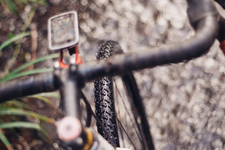 View over the handlebars and bike computer to the Ritchey MegaBite WCS front tyre on wet stony ground.