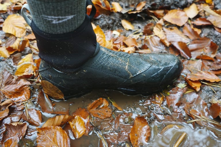 Side view of a Northwave Magma XC Core worn in a wet, leaf-strewn puddle, showing the black neoprene collar.
