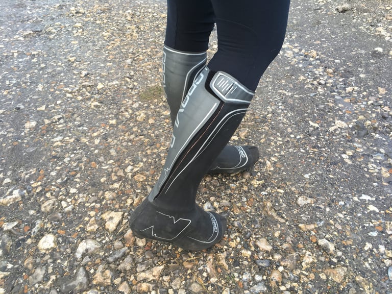 Side view of SPATZ GravlR overshoes showing the full-length outer zip and velcro flap, on a wet gravel path.