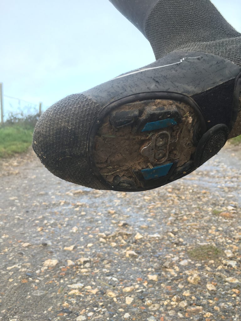 Sole of a SPATZ GravlR overshoe with a cut-out for the cleat and Kevlar-reinforced toe, caked in mud.