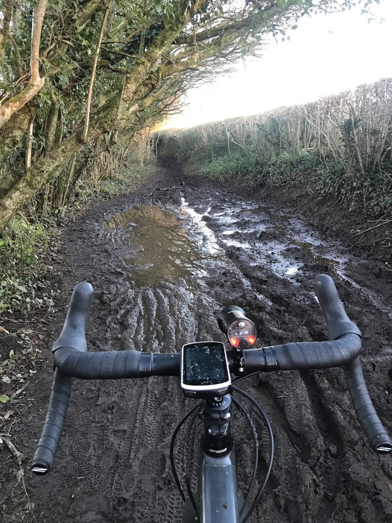 View over drop bars with a GPS unit and front light down a deeply muddy lane near Cardiff on the final Festive 500 day.
