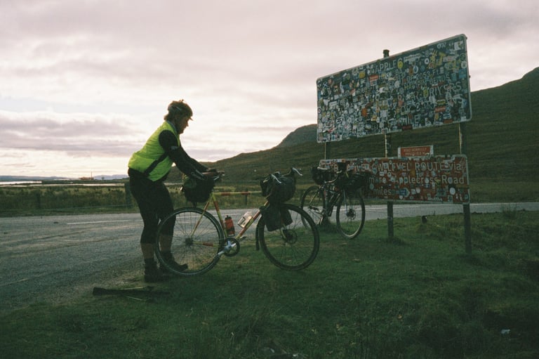 Lewis flips his rear wheel to change gear beside the sticker-covered Bealach na Bà sign at the foot of the climb.
