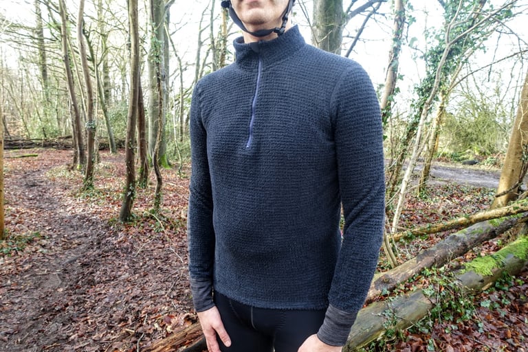 Front of the navy Velocio Alpha long sleeve jersey with half zip and high collar, worn on a woodland trail.