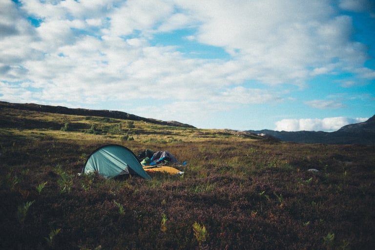 Green tent pitched on heather moorland under a broken sky, the wild camp beyond Shieldaig on the NC500.