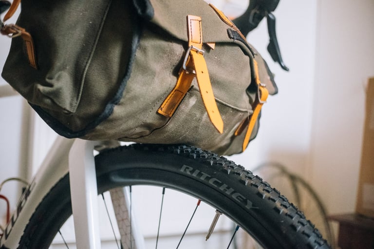 Carradice saddlebag strapped to the handlebars sags onto the front tyre, the problem the DIY support solves.