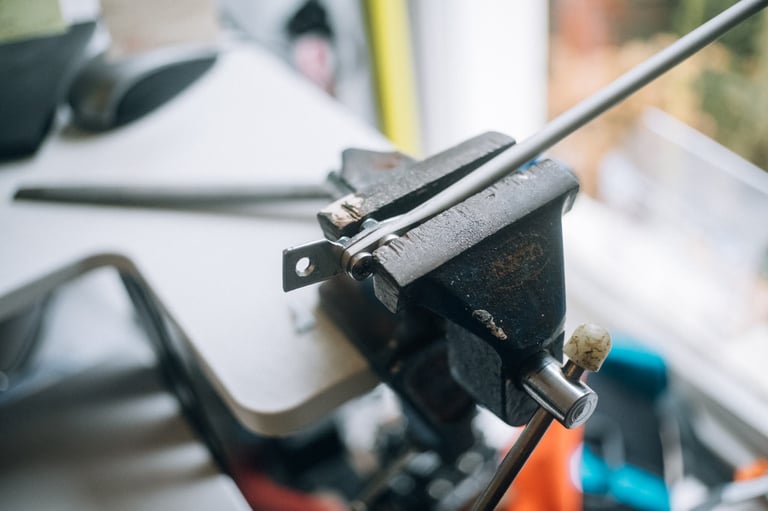 Fork-mounted strut with a home-made bracket cut from mending bar, clamped in a vice for shaping.