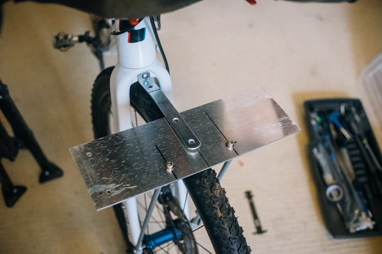 Aluminium plate bolted to the struts, with a right-angle bar braced from the fork crown to stop it twisting.