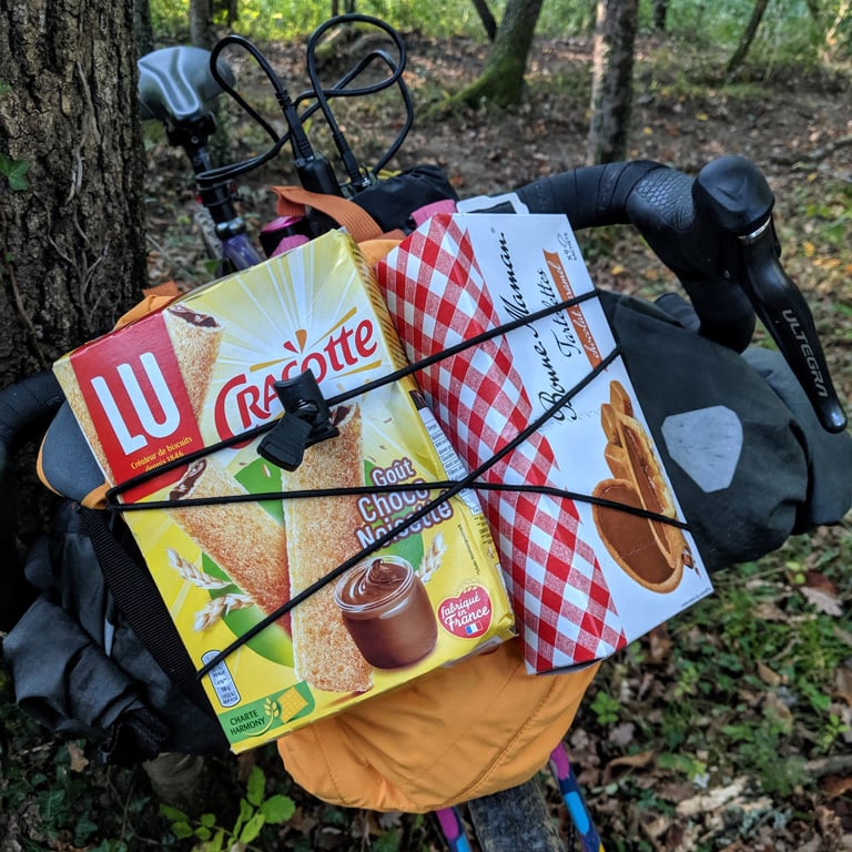 Two boxes of French biscuits held under the bungee cord on top of an Ortlieb handlebar pack.