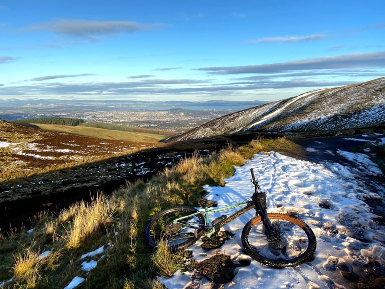 Cale AL lies on a snowy hillside in the Pentland Hills, with Edinburgh and the Firth of Forth in the distance.