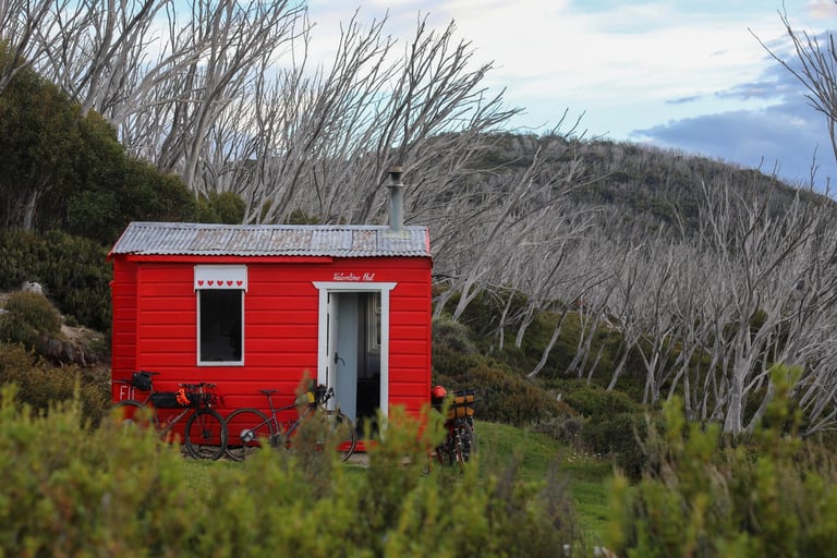 Red Valentine Hut emergency shelter in the Jagungal Wilderness with bikepacking bikes leant against it.