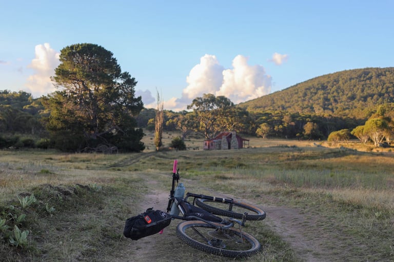Bikepacking bike lies on a track with Westermans Homestead behind, the finish of the Capital Divide route.