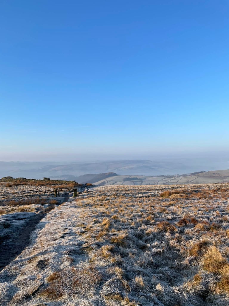 Frosty moorland path under a clear blue sky above misty fields near Sheffield on an early-morning ride.