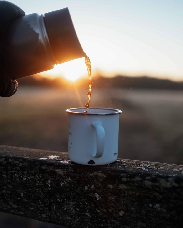 Tea poured from a flask into a white enamel mug at sunrise in Cornwall, ticking off the hot flask tile.