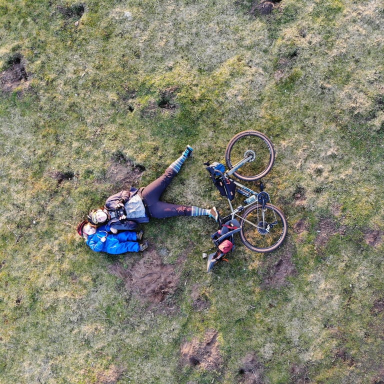 Aerial view of a rider and a toddler lying on the grass beside a loaded bike, the youngest entrant in the 2021 event.