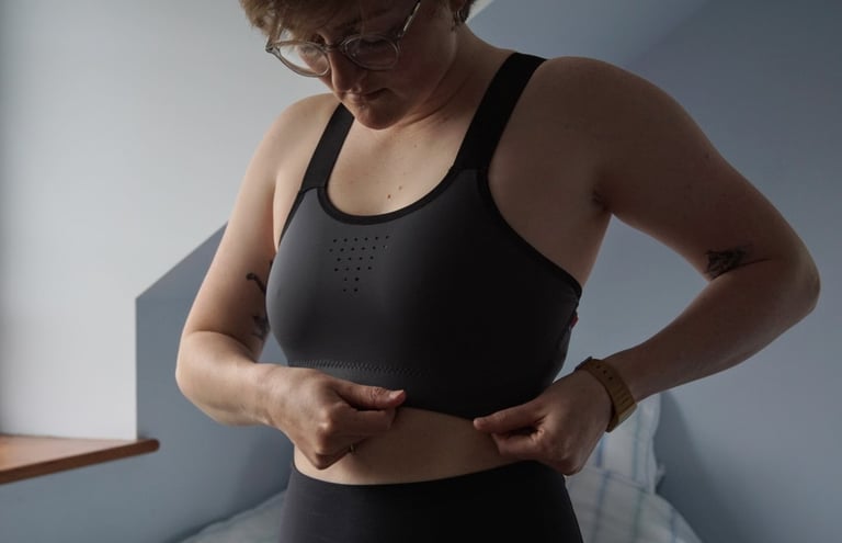 Rider checking the fit of the Velocio LUXE bra in size large, holding the elastic band around the ribcage.