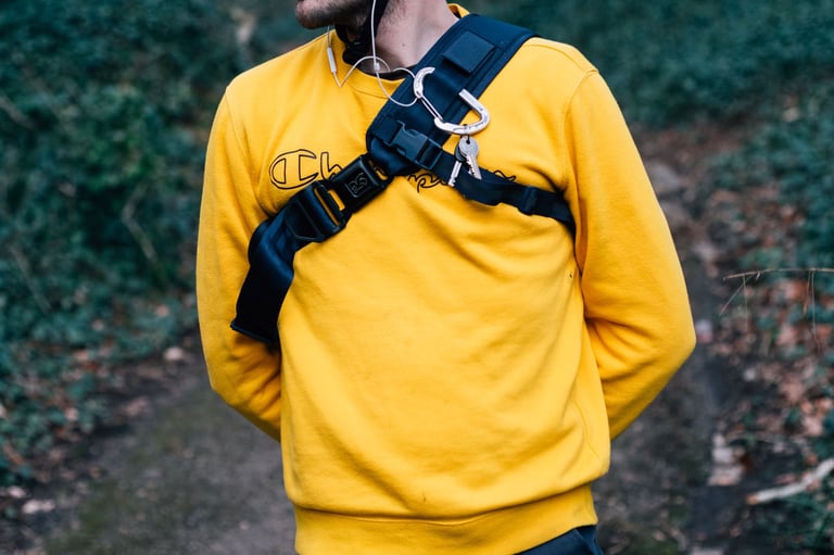 Kadet sling bag chest strap with seatbelt-style buckle, stabilisation strap and a carabiner holding keys.