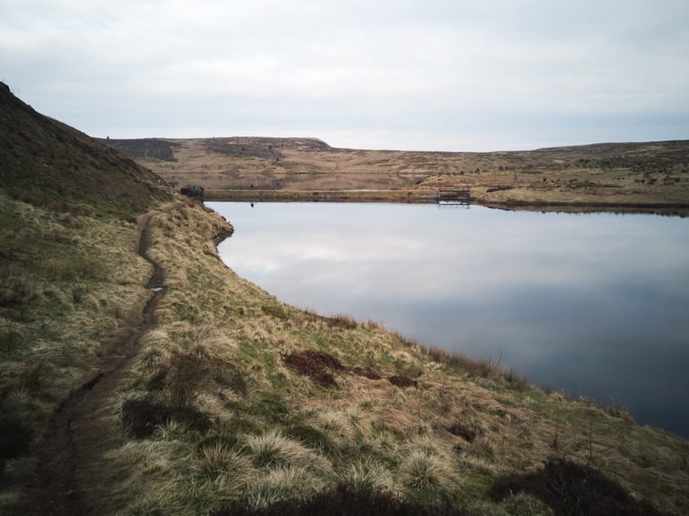 Narrow singletrack path skirting the shore of Cochno Loch on the Glasgow Inner Circle route.