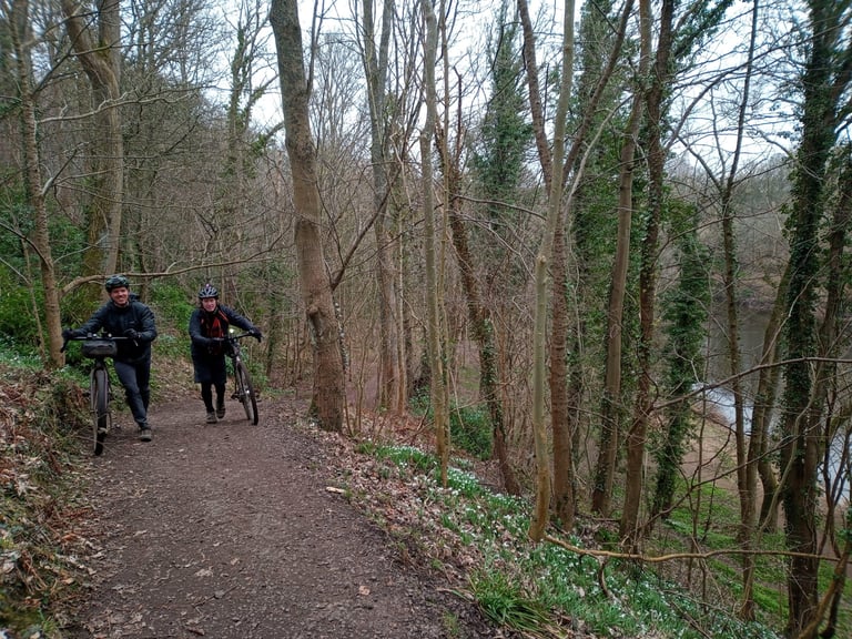 Two riders push bikes up a wooded path above the River Clyde near Bothwell on the Glasgow Inner Circle.