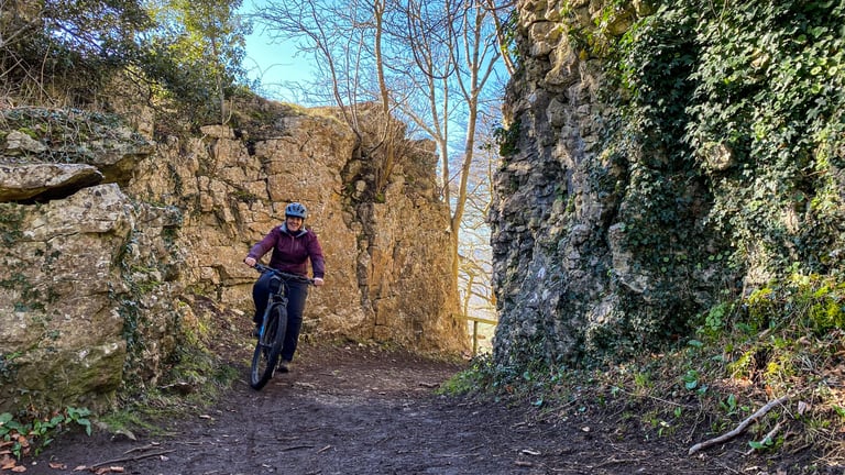 Smiling rider on a mountain bike through a narrow rock cutting in the Wye Valley on a The (Socially) Distance(d) ride.