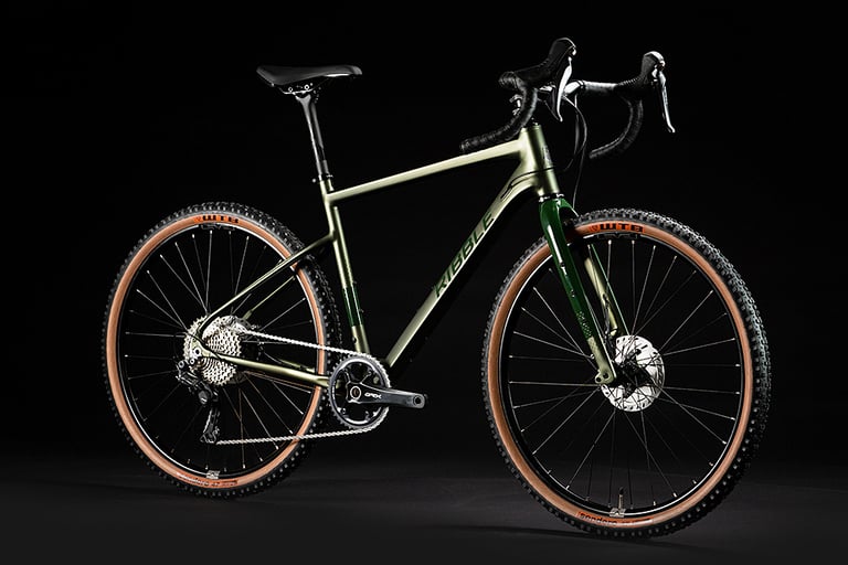 Ribble Gravel AL alloy gravel bike in khaki green with GRX cranks and tan-wall WTB tyres, shot against black.