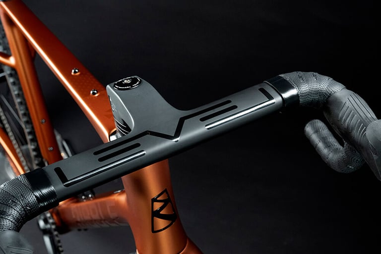 Close-up of the integrated aero bar and stem on a copper-orange Ribble Gravel SL, with black bar tape.