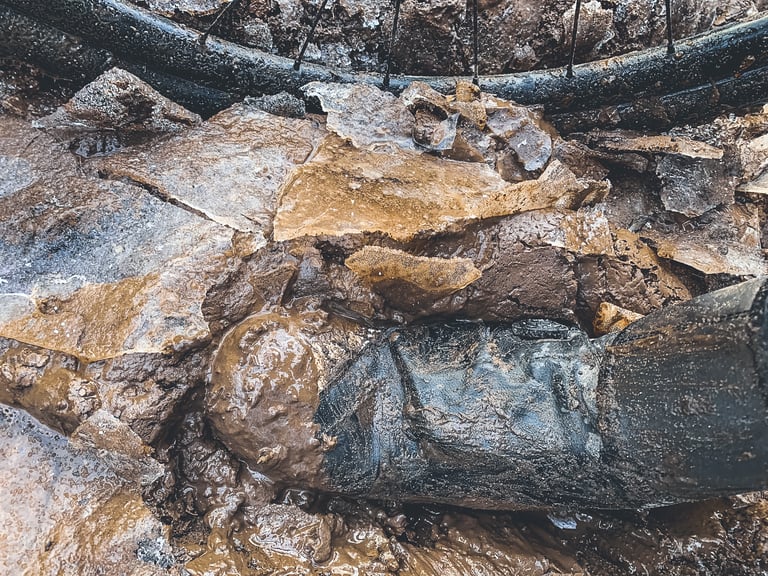 Mud-caked Specialized Defroster boot sunk in thick cracked mud beside a bike wheel during winter testing.