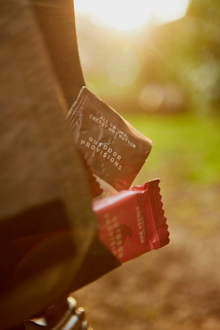 Outdoor Provisions nut butter and energy bar wrappers poking out of a jersey pocket in low evening sun.