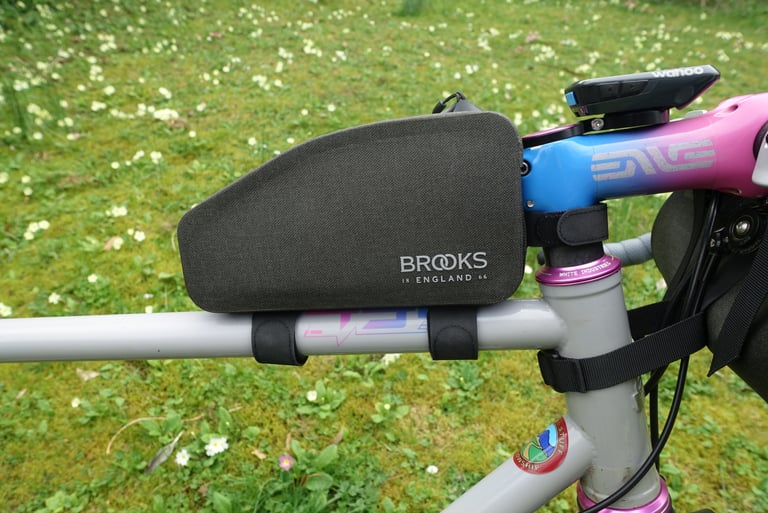 Brooks Scape Top Tube Bag mounted behind a pink and blue ENVE stem on a grey bike, with a Wahoo computer above.