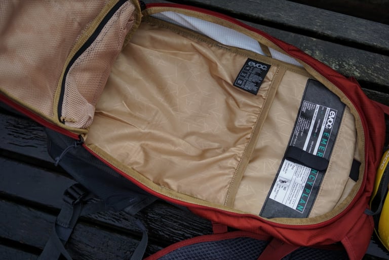 EVOC Ride 12L main compartment unzipped fully open, showing the mesh flap pockets and the beige liner.