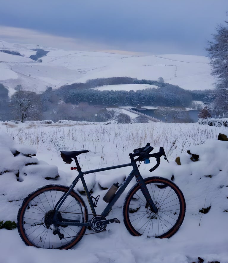 Mike Gaskell's Mason Bokeh gravel bike in snow on a hillside above a reservoir, with white Peak District hills behind.