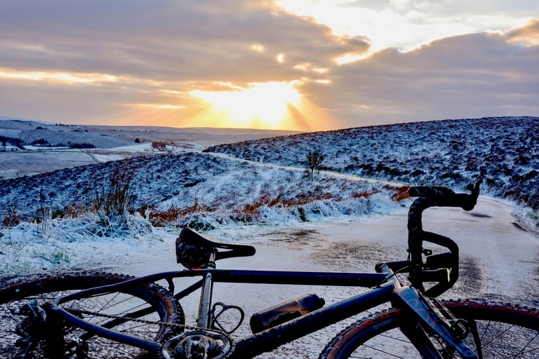 Gravel bike on a snow-dusted road in the Peak District near Macclesfield as the sun breaks through cloud.