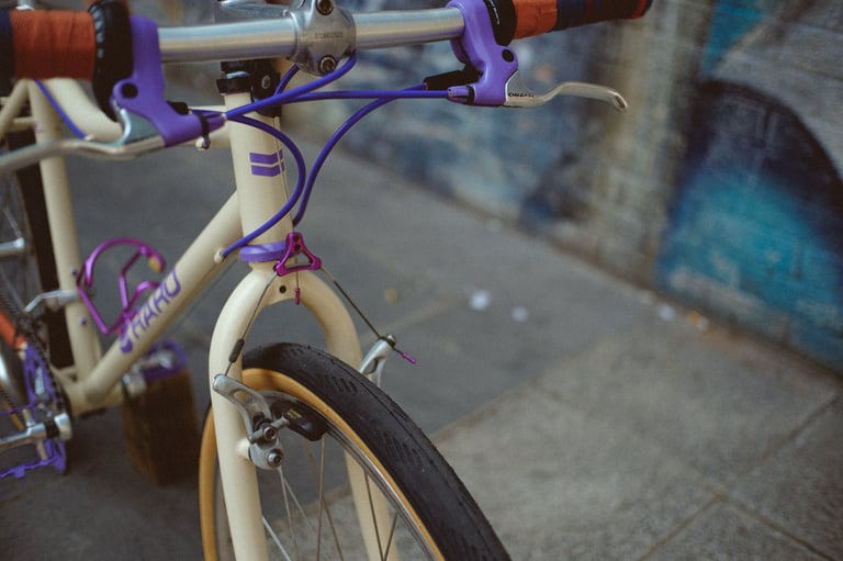 Front end of a cream Haro vintage mountain bike with purple cables and a cantilever rim brake on the front wheel.