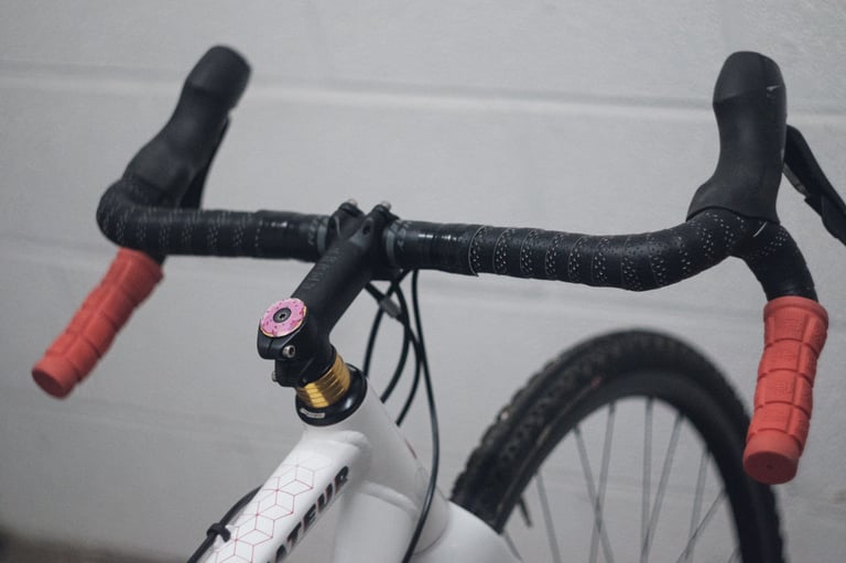 Ritchey Venturemax flared bars with red grips on the drops, black tape and a doughnut stem cap.