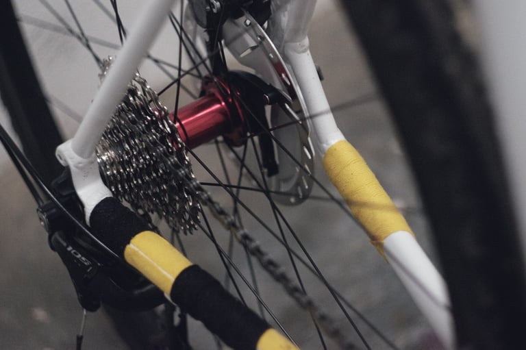 Yellow and black cotton tape wrapped round the chain stay and seat stay beside a red rear hub.