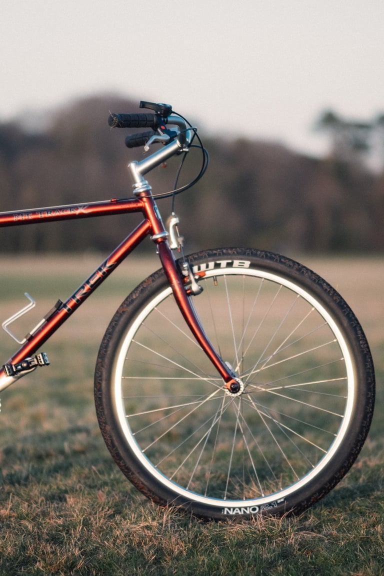 Front half of a red vintage Trek Mt. Track mountain bike with a 26-inch WTB Nano tyre, parked on grass.