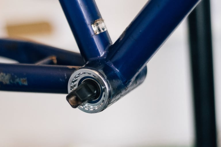 Square taper bottom bracket in the shell of a blue steel vintage MTB frame, seen close up on a workstand.