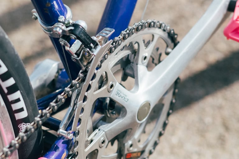 Silver Exage crankset, chainrings and front derailleur on a vintage mountain bike with a triple drivetrain.