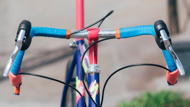 Drop bars wrapped in blue tape on a vintage MTB, with brake levers and fresh cables running from them.