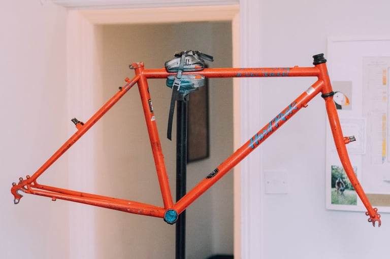 Stripped orange Hardrock mountain bike frame on a workshop stand, ready for a deep clean before a gravel conversion.