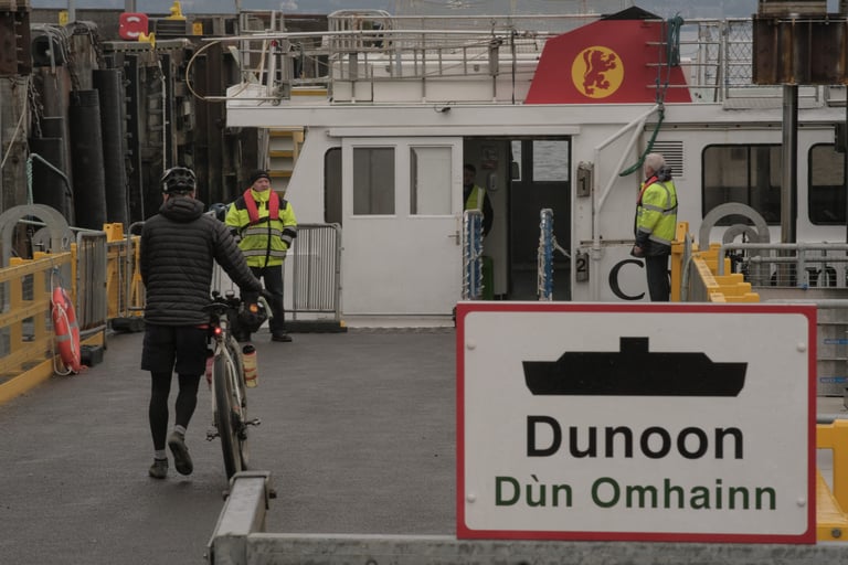 Cyclist wheels a bike past ferry crew at the Dunoon terminal on the Gourock to Dunoon crossing in Argyll.