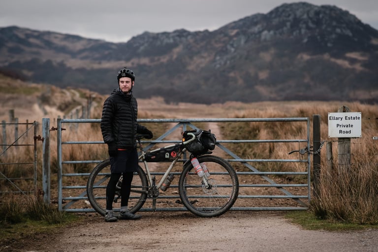Marcus Nicolson stands with his new Mason ISO gravel bike at a gate on the Ellary Estate private road in Argyll.