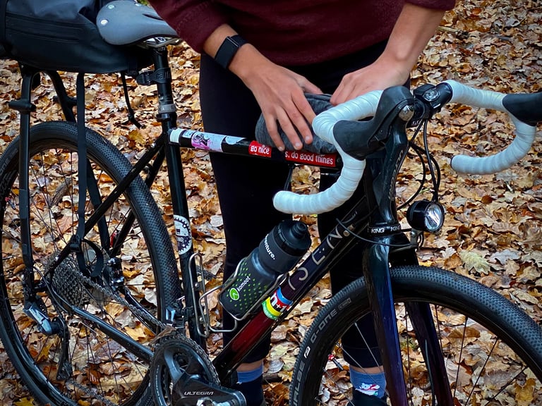 Vedangi Kulkarni's Isen gravel bike with white bar tape and Ultegra groupset as she adjusts a handlebar bag.